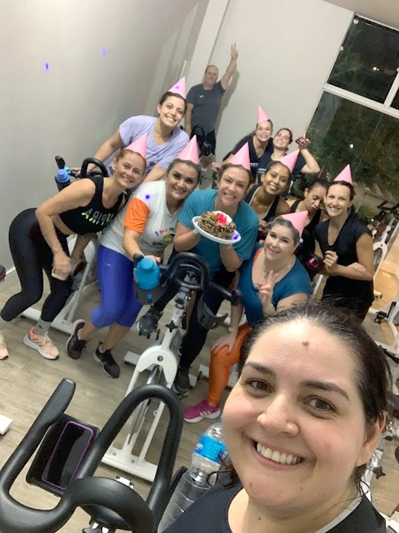 Turma da bike reunida numa comemoração, com chapéus de festa e bolo
