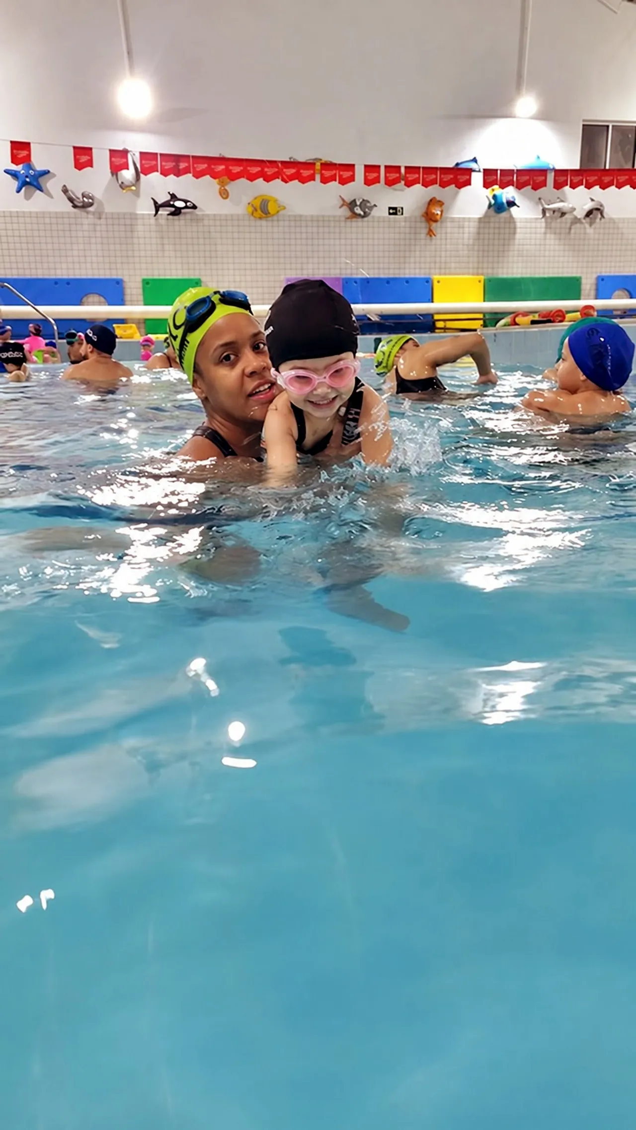 Professora com uma criança durante a aula de natação infantil
