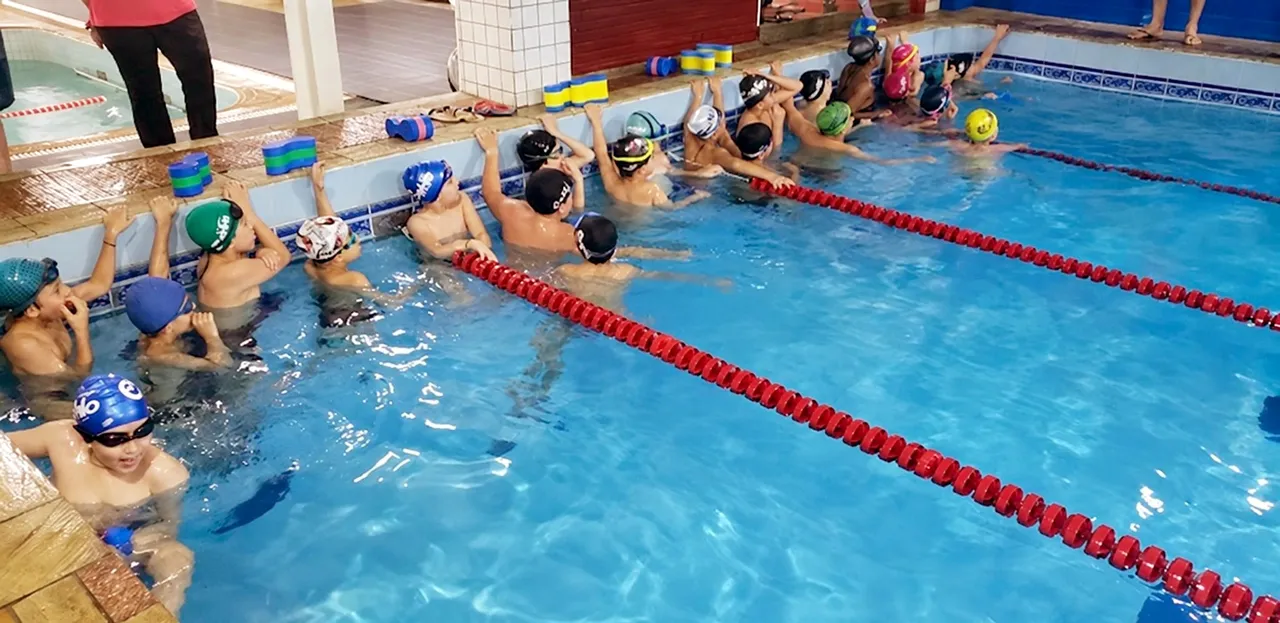 Turma de crianças reunida na borda da piscina